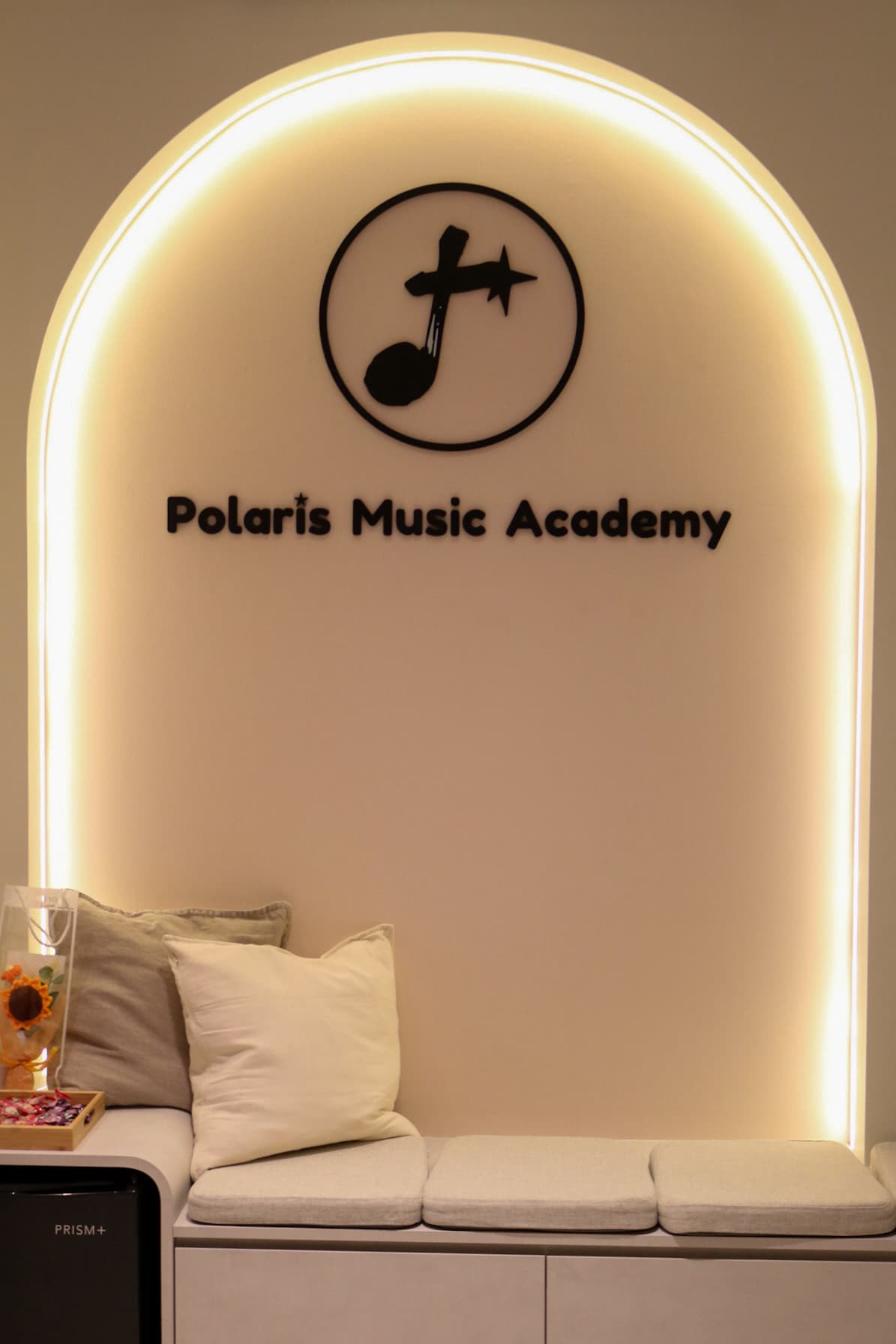 The Polaris Music Academy logo wall above the entrance bench at the studio