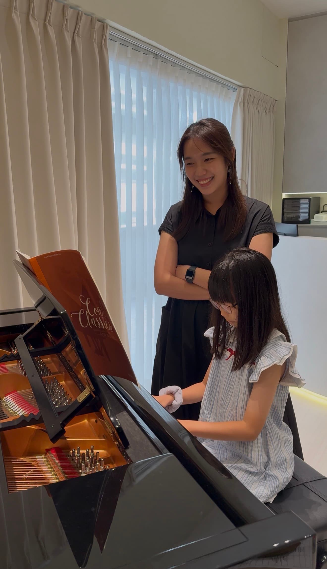Teacher Sarah guiding a student at the grand piano